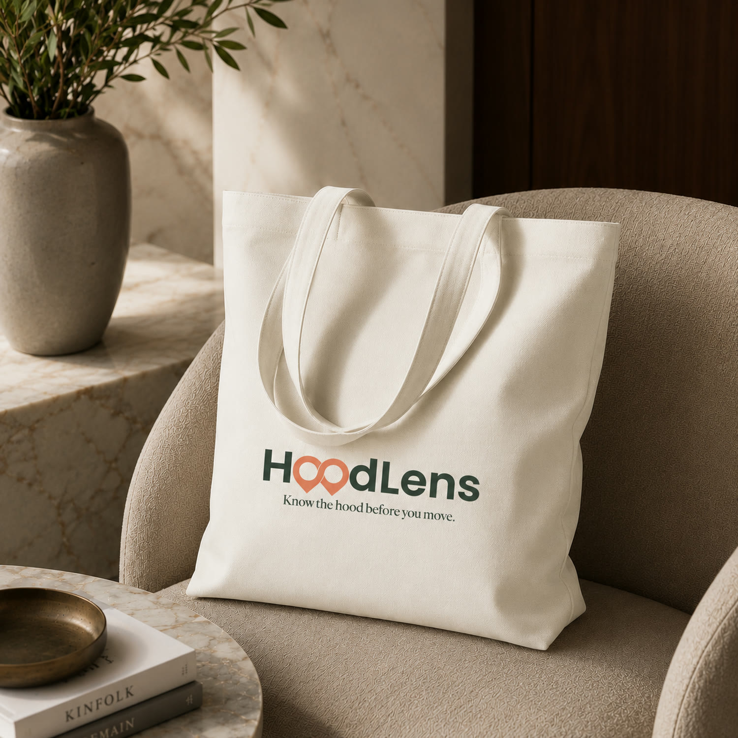 A cream tote bag printed with the HoodLens wordmark and the line know the hood before you move.