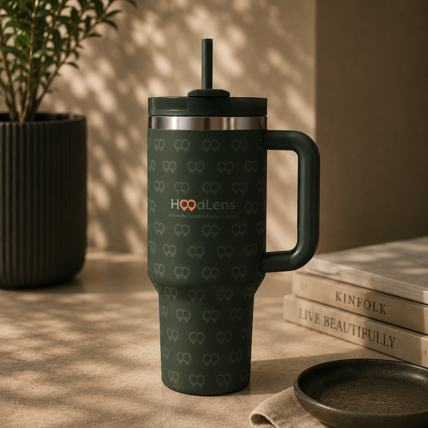 A deep forest green insulated tumbler patterned with the HoodLens mark.